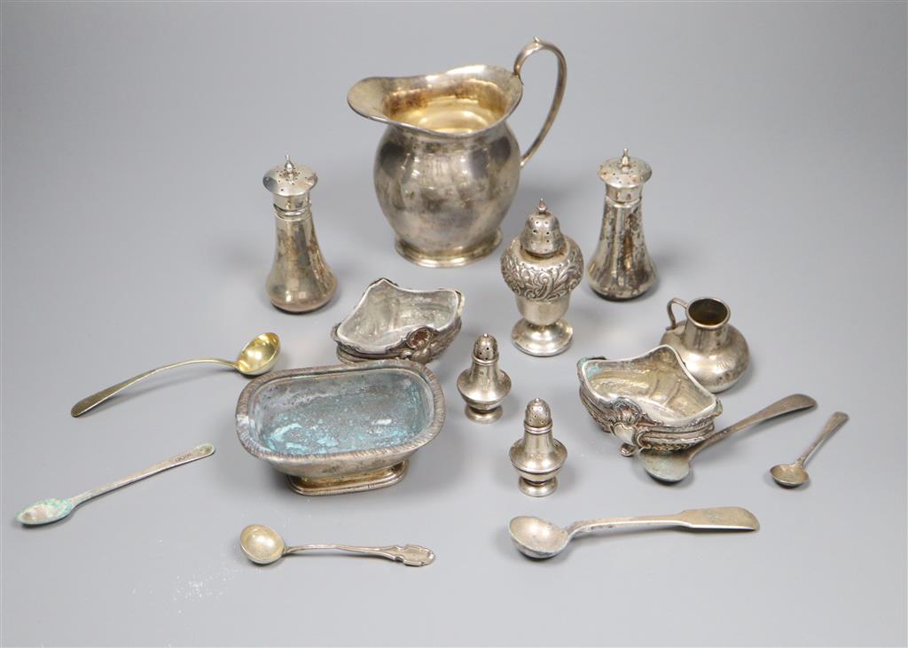 A George V silver cream jug and a collection of small silver and plated condiments and spoons.